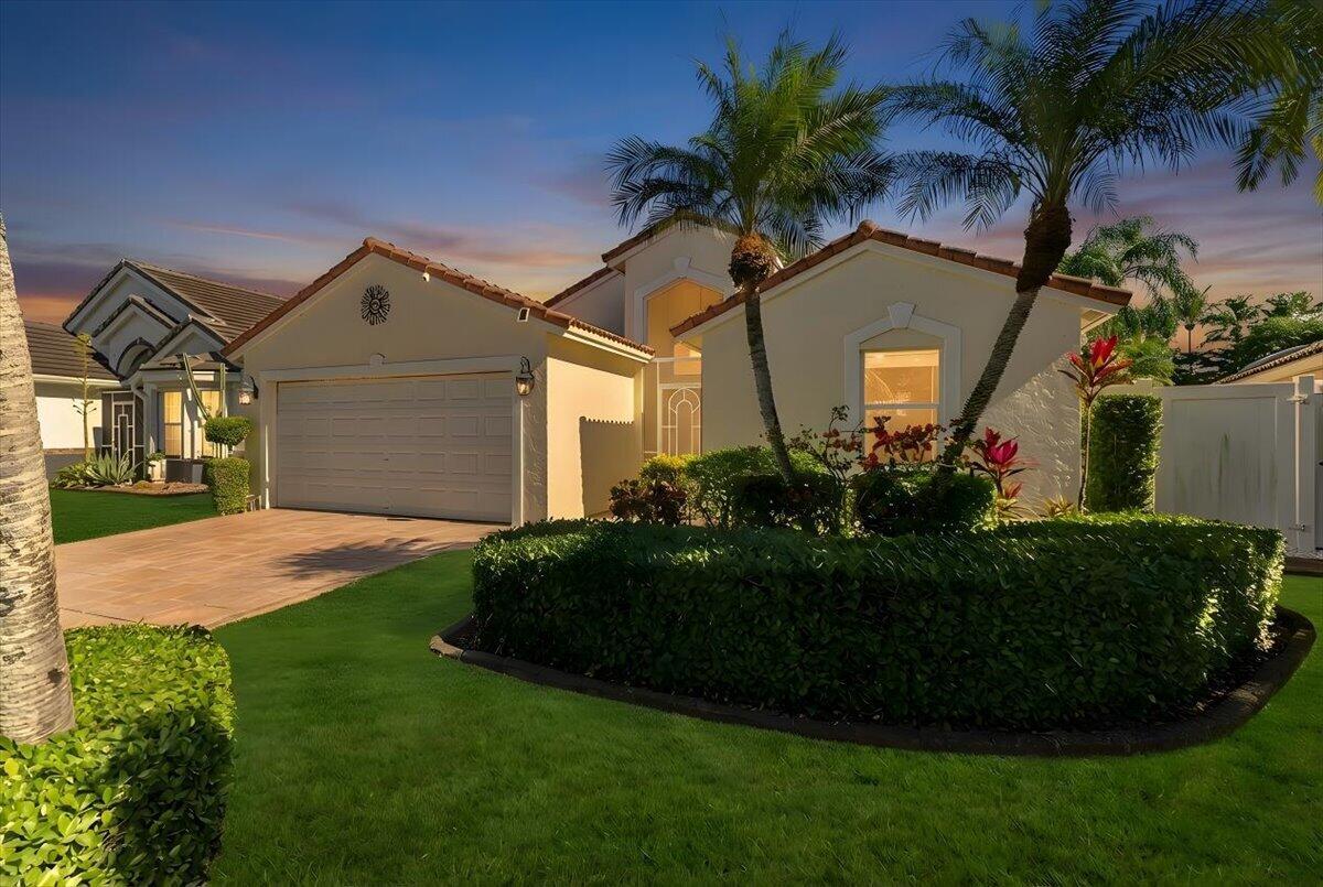 A single-story house with a two-car garage, palm trees, and a manicured hedge in front — 7534 Ironbridge Circle, Delray Beach FL 33446, DELRAY BEACH, FL