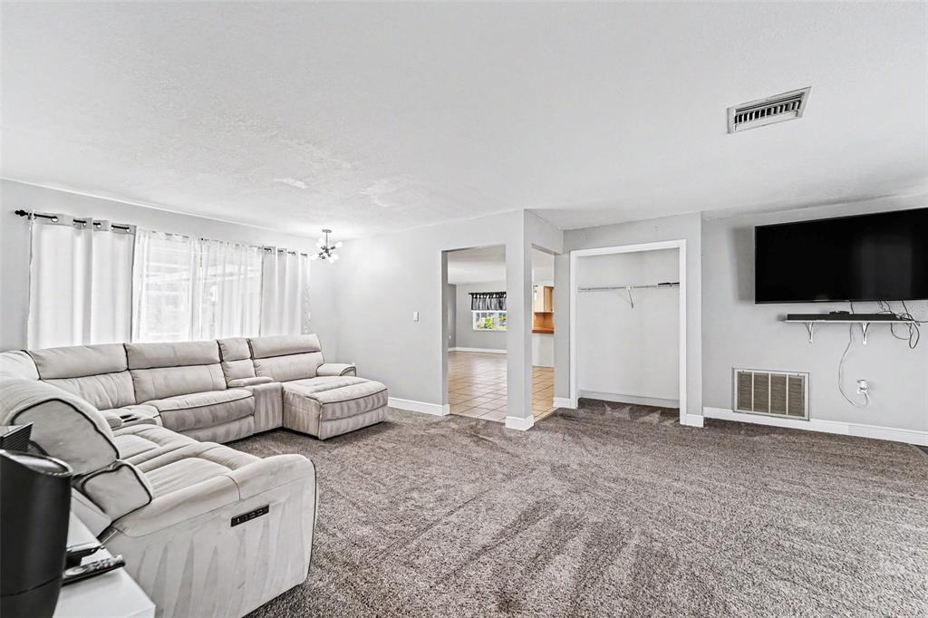 A living room features gray carpeting, a light-colored sectional sofa, and an open doorway — 8040 SAYBROOK DRIVE, PORT RICHEY, FL