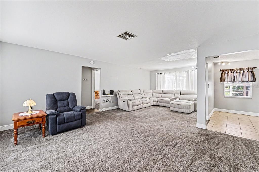A living room features gray carpeting, a blue recliner, and a large light-colored sectional sofa — 8040 SAYBROOK DRIVE, PORT RICHEY, FL