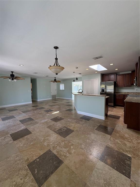 An open-concept kitchen and living area features travertine tile flooring and dark wood cabinetry — 218 LEWIS BOULEVARD SE, ST PETERSBURG, FL