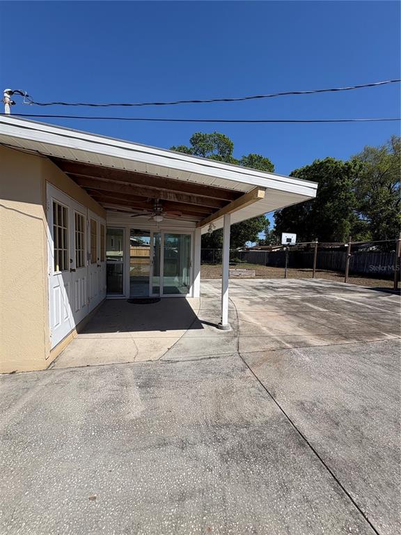 A concrete patio area features a covered porch with a ceiling fan and glass doors — 218 LEWIS BOULEVARD SE, ST PETERSBURG, FL