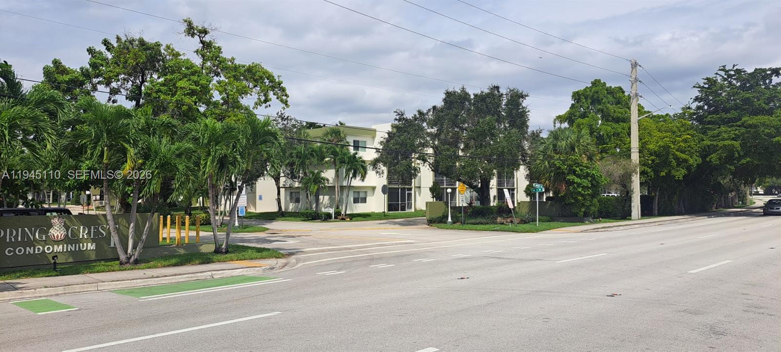 The exterior of a multi-story condominium complex features palm trees and a prominent entrance sign — 4255 N University Dr # 315, Sunrise FL 33351, SUNRISE, FL