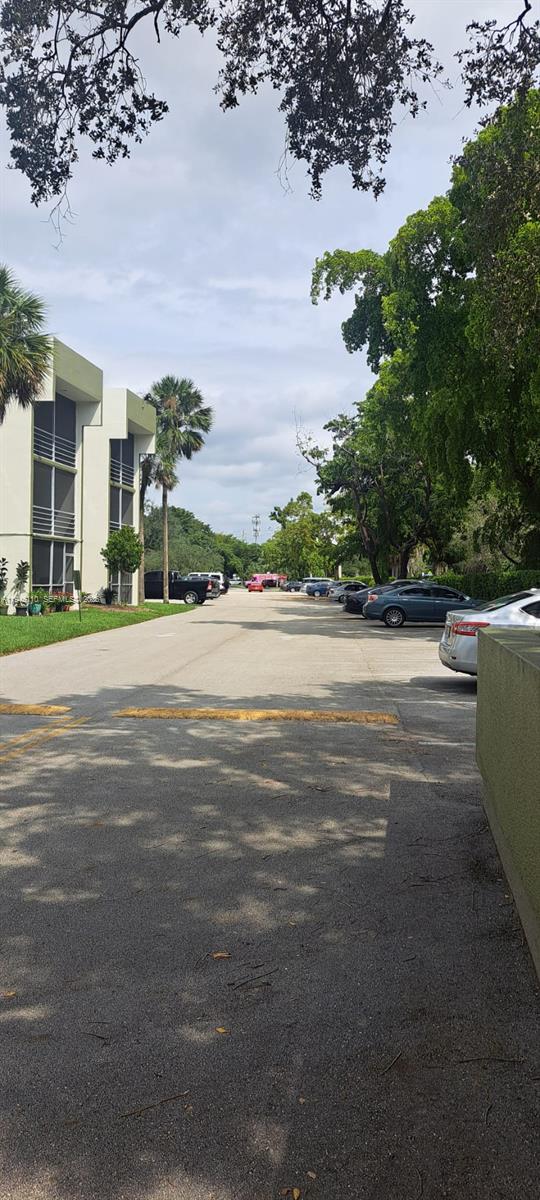 A paved parking lot sits between a multi-story apartment building and a line of trees — 4255 N University Dr # 315, Sunrise FL 33351, SUNRISE, FL