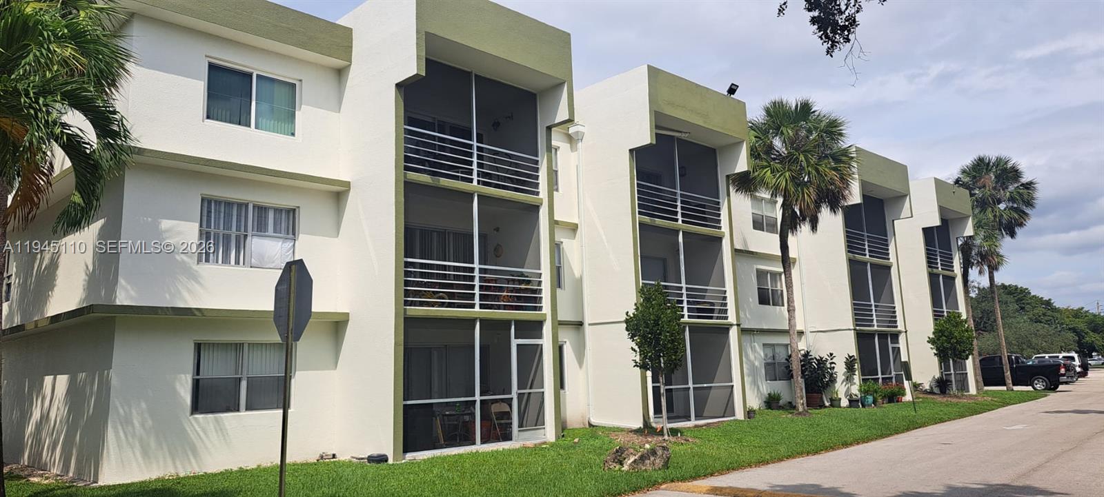 A three-story apartment building with white stucco walls, green trim, and screened-in balconies — 4255 N University Dr # 315, Sunrise FL 33351, SUNRISE, FL