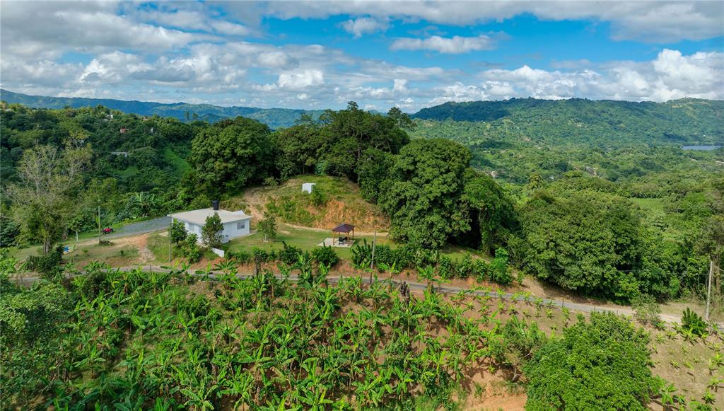 An aerial view shows a white house and a gazebo surrounded by lush green hills — Carr. 140 KM 17.9, UTUADO, PR