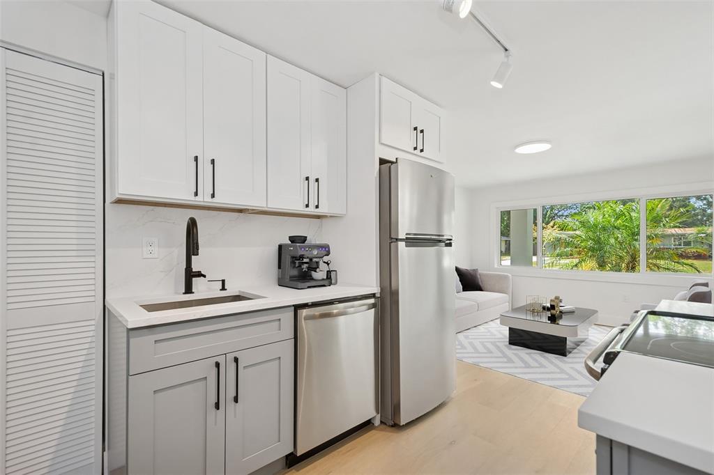 A kitchen with gray lower cabinets, white upper cabinets, stainless appliances, and an adjacent living area — 2655 BAY STREET UNIT 2, SARASOTA, FL