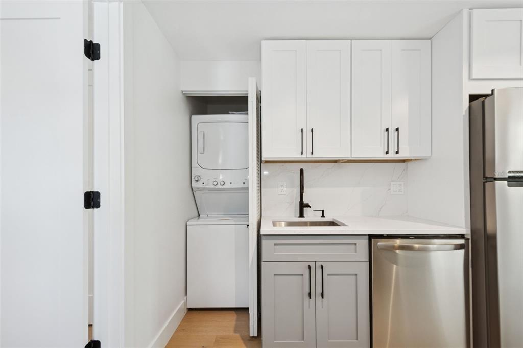 A small kitchen area features white upper cabinets, gray lower cabinets, and a stacked laundry unit — 2655 BAY STREET UNIT 2, SARASOTA, FL