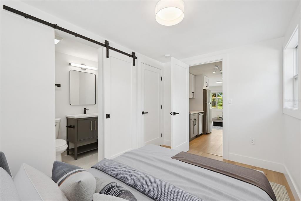A bedroom features a sliding barn door to a bathroom and an open doorway to a kitchen — 2655 BAY STREET UNIT 2, SARASOTA, FL