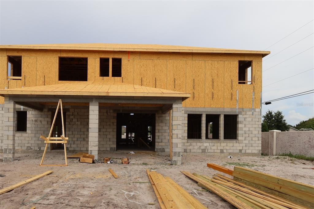 An unfinished room under construction features exposed wooden wall studs, roof trusses, and installed windows — 2568 HAWKS OVERLOOK, OVIEDO, FL