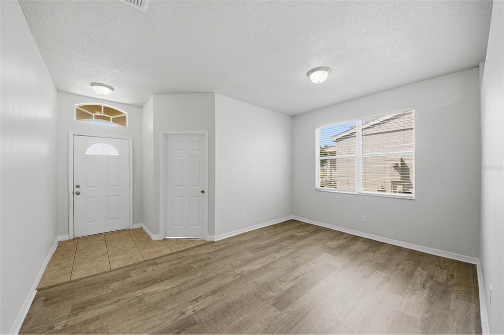 An entryway with tile flooring leads into a living room featuring wood-look flooring and windows — 949 WHISPERING CYPRESS LANE, ORLANDO, FL