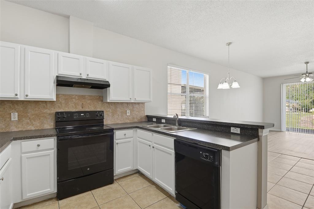 A kitchen with white cabinets, black appliances, dark countertops, and tile flooring — 949 WHISPERING CYPRESS LANE, ORLANDO, FL