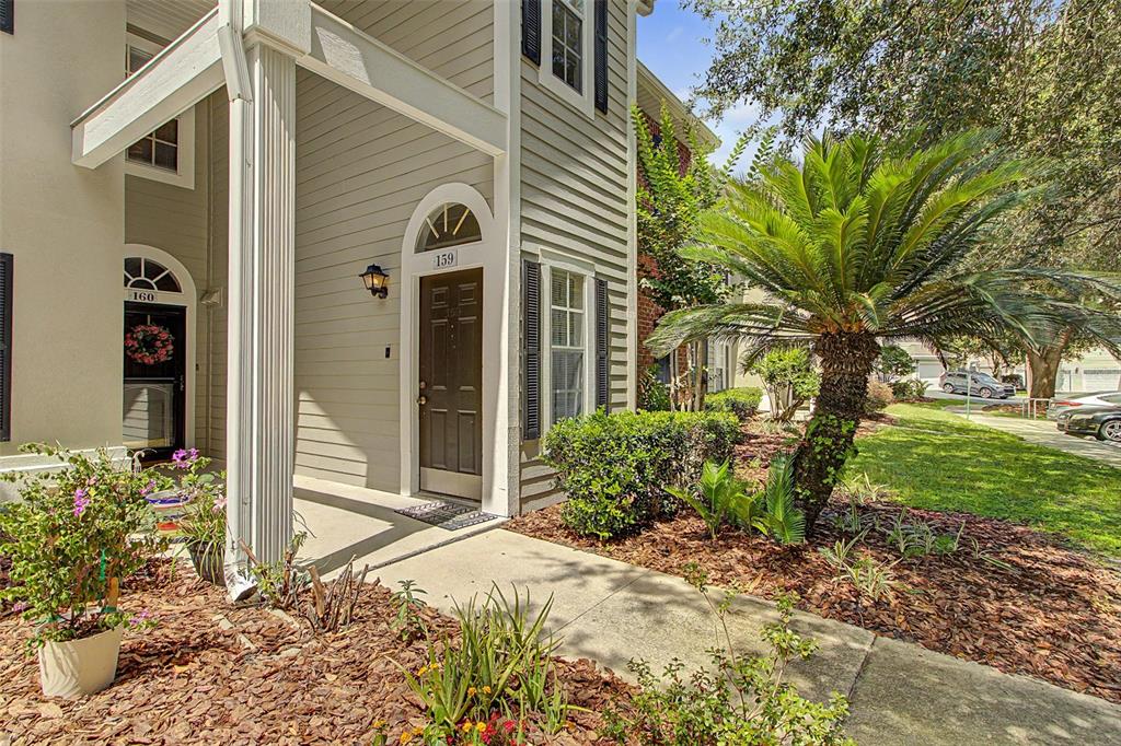 A view of the exterior entrance to two residential units with a palm tree nearby — 10000 SW 52ND AVENUE UNIT AA-159, GAINESVILLE, FL