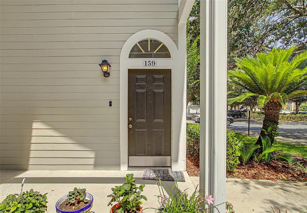 A brown front door with a transom window is set into a light-colored siding exterior — 10000 SW 52ND AVENUE UNIT AA-159, GAINESVILLE, FL