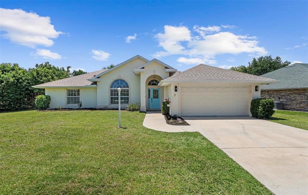 A single-story house with a light-colored exterior, a two-car garage, and a blue front door — 3 LEWIS DRIVE, PALM COAST, FL