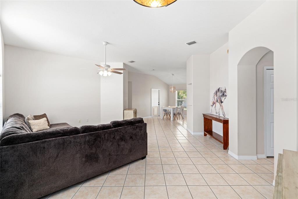 A living room with tile flooring, a dark sofa, and a dining area beyond — 3 LEWIS DRIVE, PALM COAST, FL