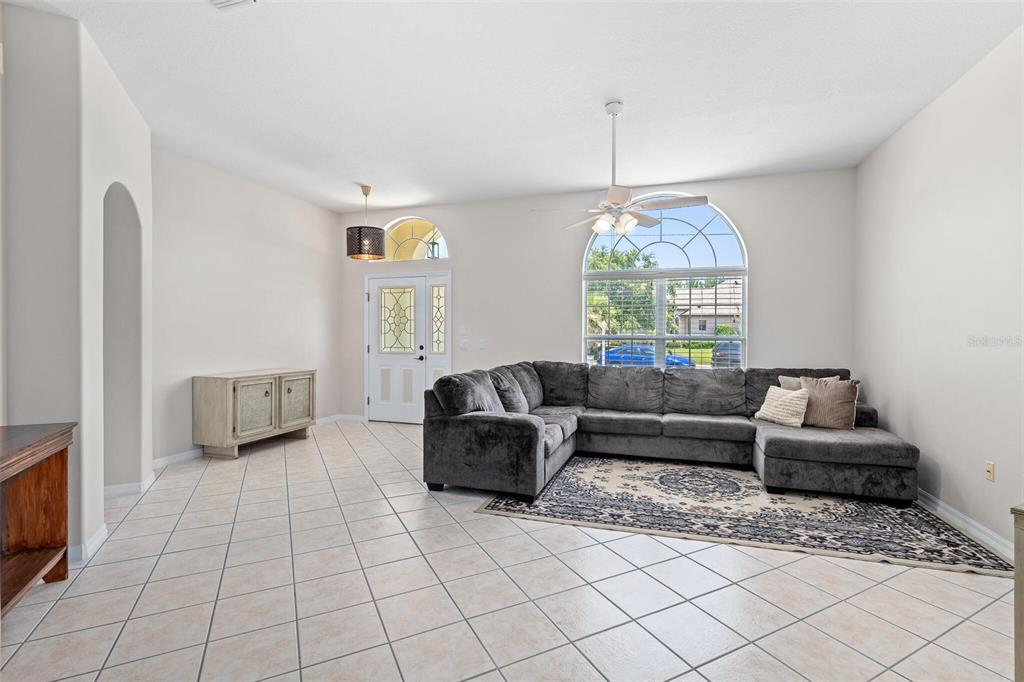 A living room features light tile floors, a large gray sectional sofa, and an arched window — 3 LEWIS DRIVE, PALM COAST, FL