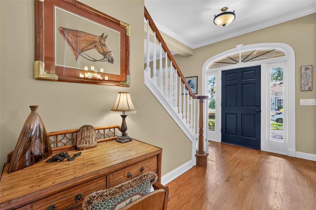 An entryway features a dark blue front door, a wooden staircase, and a bamboo console table — 900 BRIGHTWATER CIRCLE, MAITLAND, FL