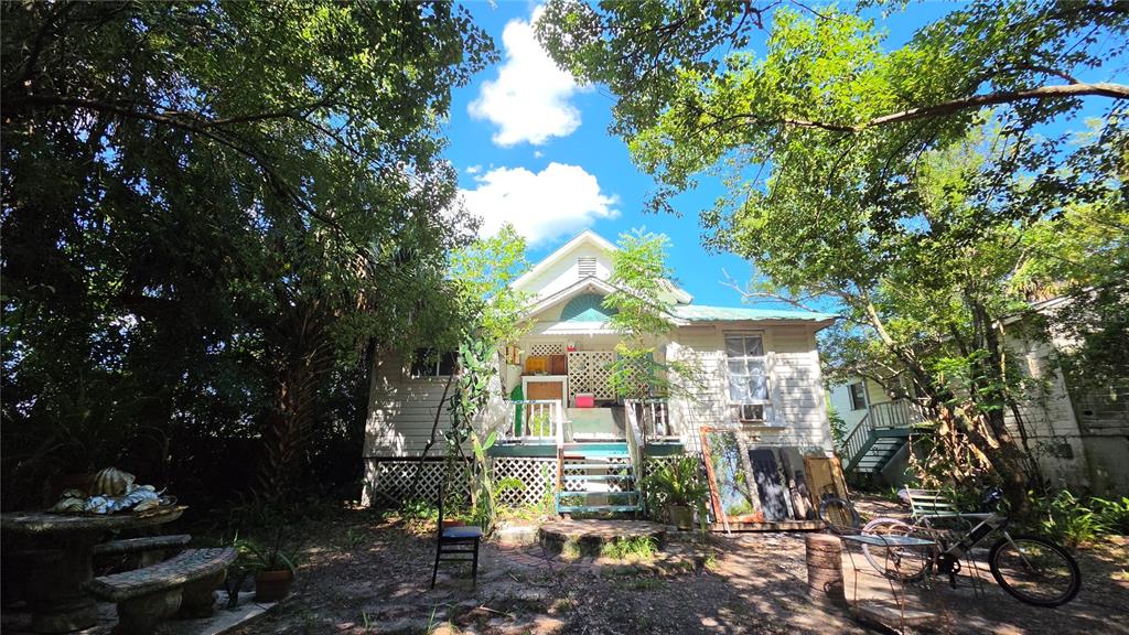 A white wooden house with a front porch sits in a yard with trees — 236 N AMELIA AVENUE, DELAND, FL