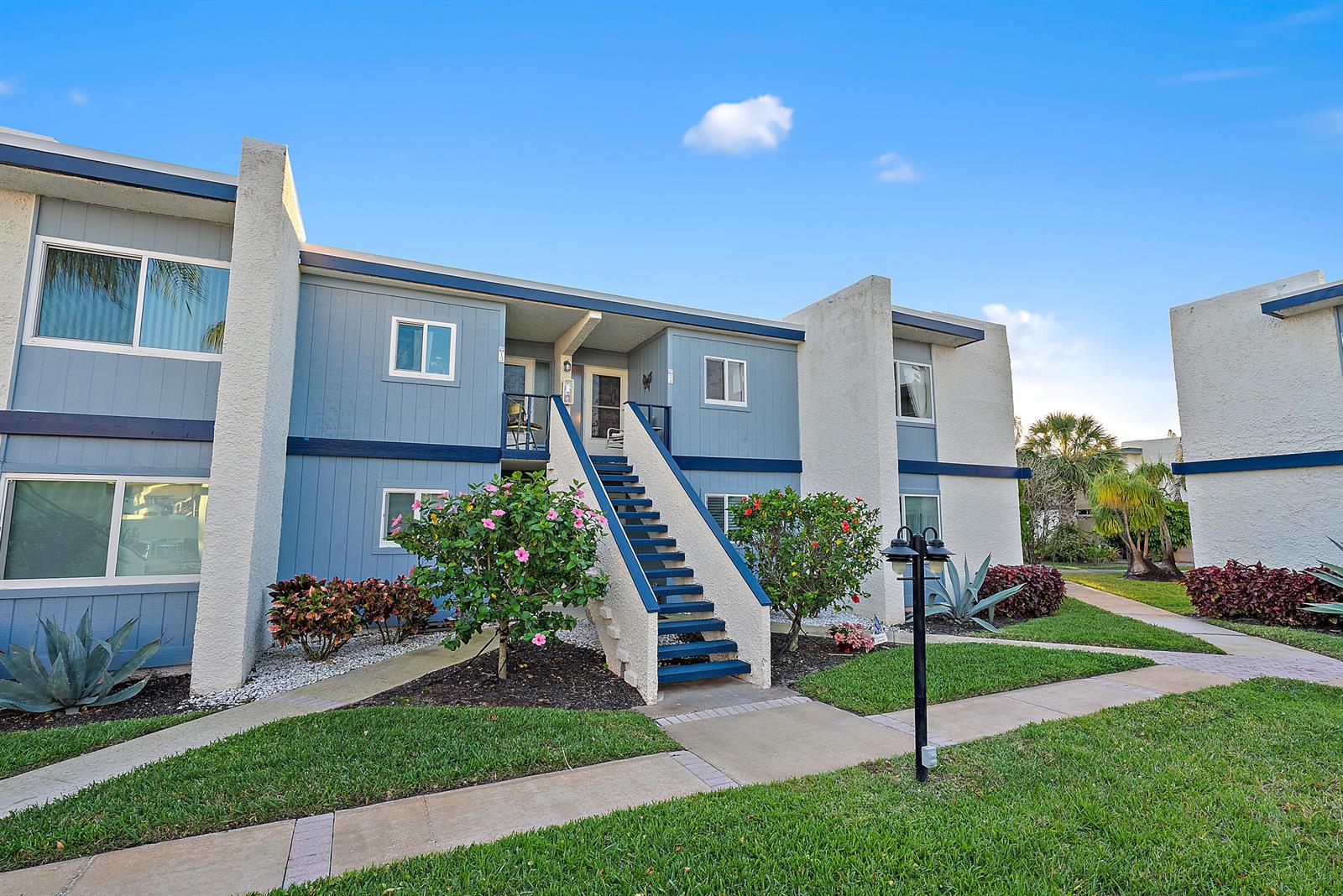 A two-story blue apartment building features an exterior staircase leading to an upper-level entrance — 1561 NE 12th Terrace # C14, Jensen Beach FL 34957, JENSEN BEACH, FL