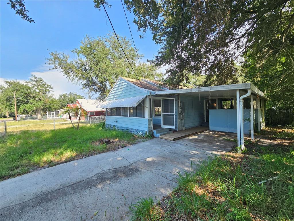 A light blue single-story house with a carport and a screened-in front porch — 2441 E MAGNOLIA STREET, LAKELAND, FL