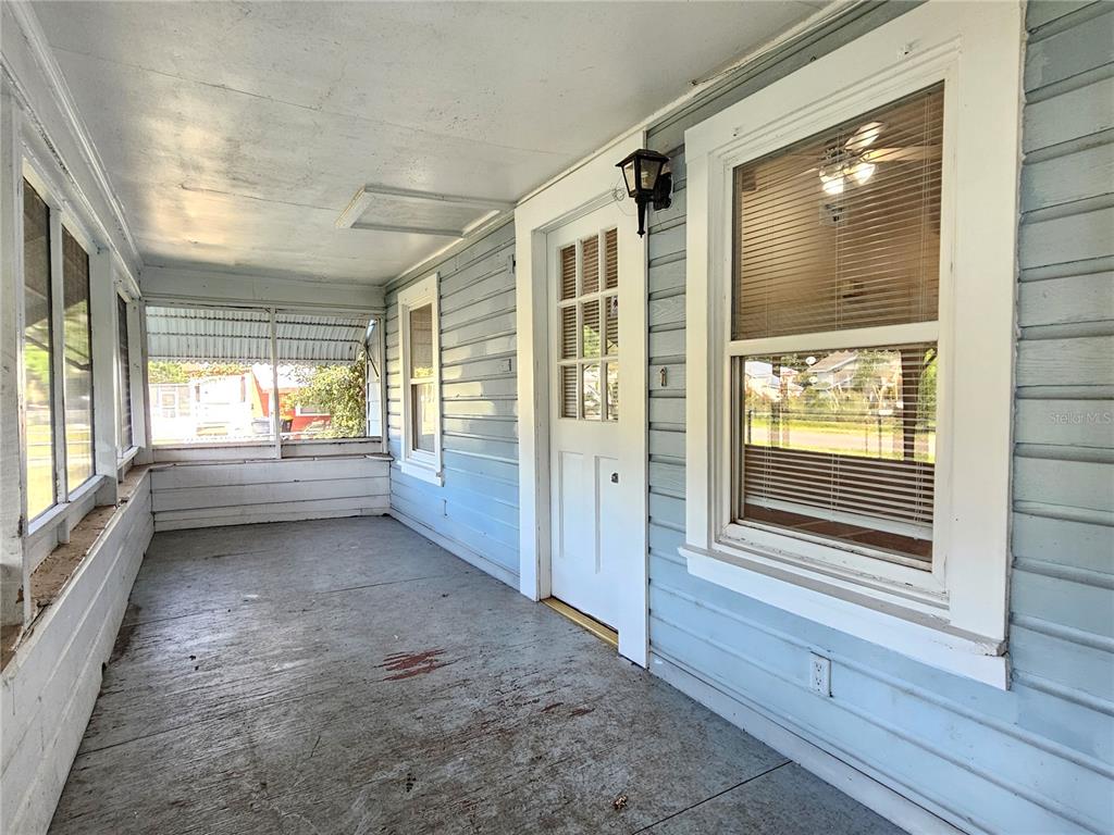A covered porch with light blue siding, a white door, and large windows — 2441 E MAGNOLIA STREET, LAKELAND, FL