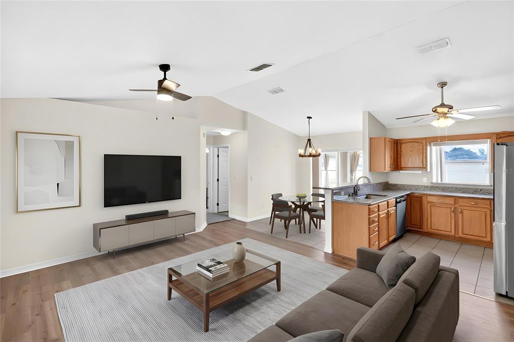 An open-concept living room and kitchen featuring wood flooring, a ceiling fan, and wooden cabinets — 4849 NW 46TH AVENUE, OCALA, FL