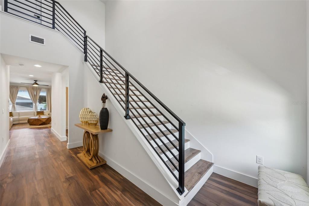A modern staircase with black metal railings leads to an upper level in a hallway — 7302 S ELLIOTT STREET, TAMPA, FL