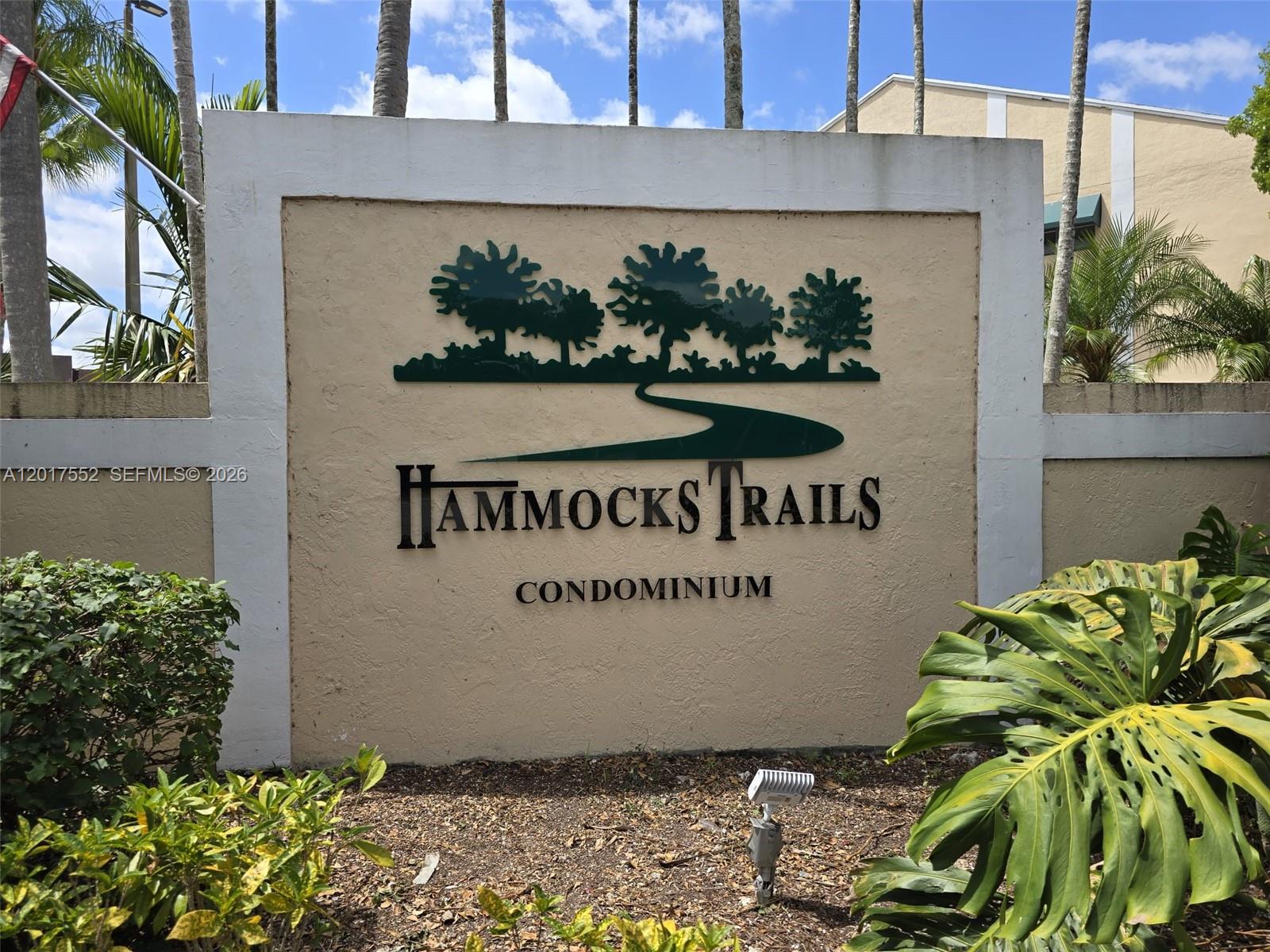 A sign for Hammocks Trails Condominium stands outdoors surrounded by palm trees and landscaping — 15320 SW 106th Ter # 1108, Miami FL 33196, MIAMI, FL