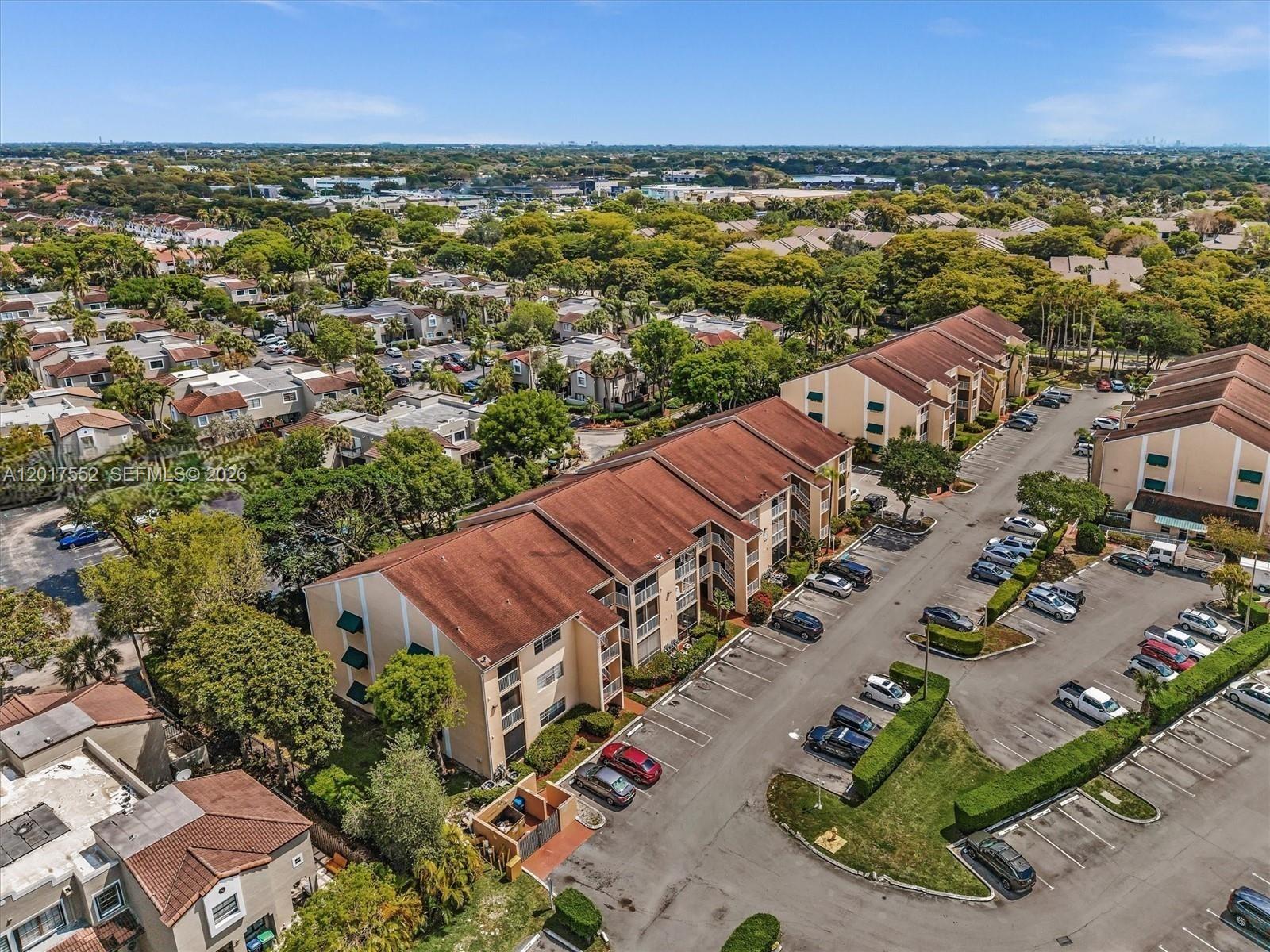 An aerial view shows multi-story apartment buildings surrounded by parking lots and lush green trees — 15320 SW 106th Ter # 1108, Miami FL 33196, MIAMI, FL