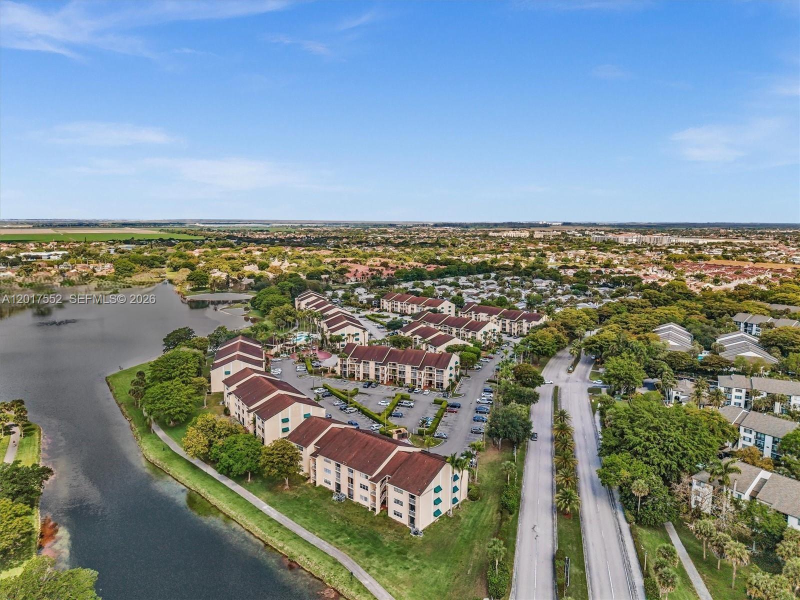 An aerial view shows multi-story residential buildings situated next to a lake and a road — 15320 SW 106th Ter # 1108, Miami FL 33196, MIAMI, FL