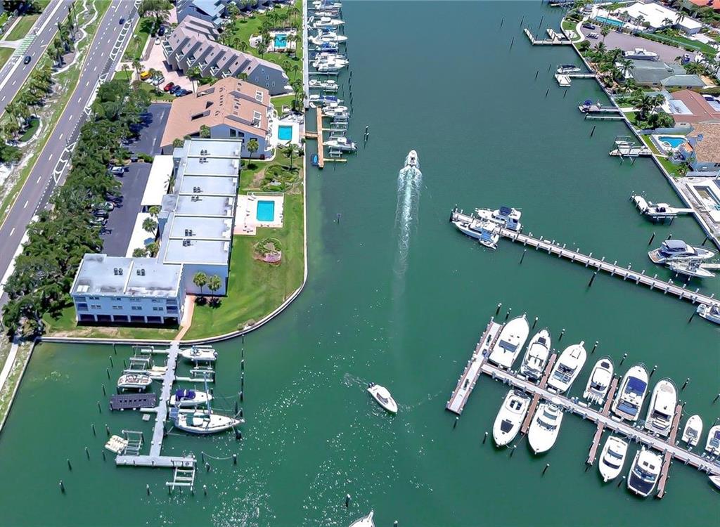An aerial view shows a canal with multiple boat docks, docked vessels, and waterfront residential buildings — 340 PINELLAS BAYWAY S UNIT 304, ST PETERSBURG, FL