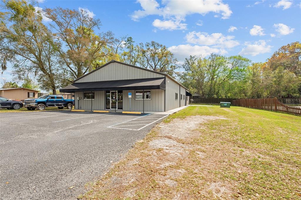 A single-story metal commercial building with a black awning and an adjacent paved parking lot — 1411 NW 23RD AVENUE, CHIEFLAND, FL