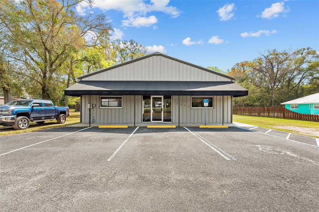 A single-story commercial building with a metal exterior, black awning, and a paved parking lot — 1411 NW 23RD AVENUE, CHIEFLAND, FL