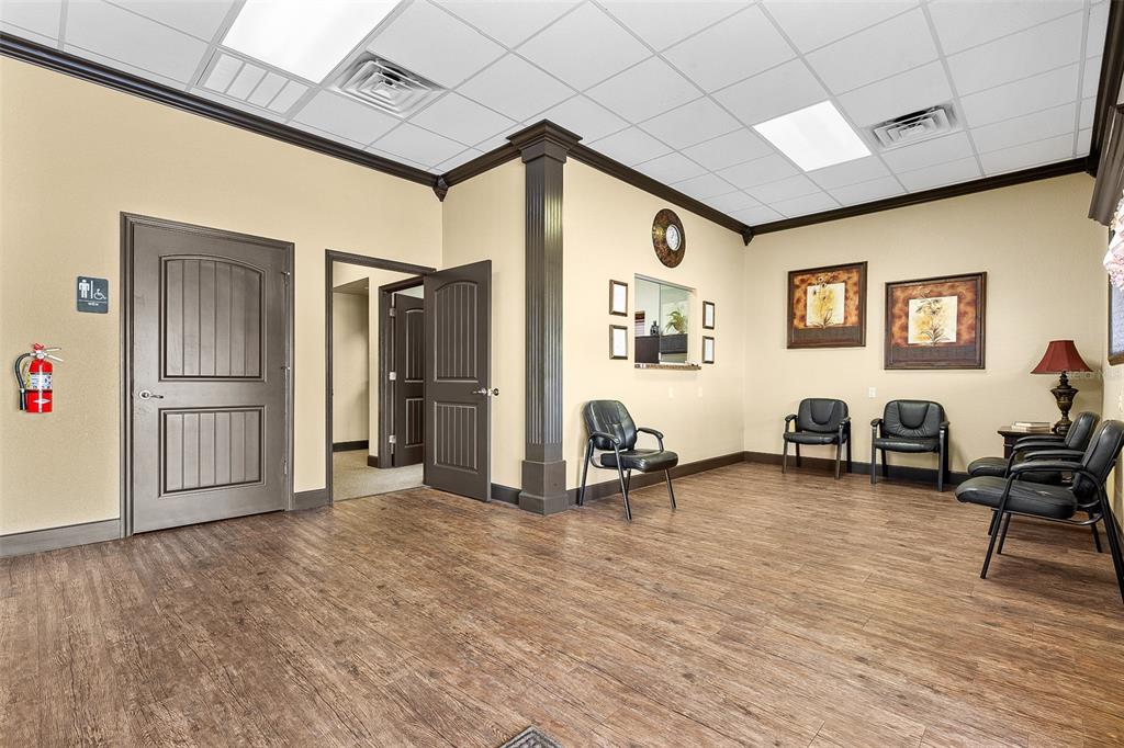 A waiting room with wood-look flooring, beige walls, black chairs, and a drop ceiling — 1411 NW 23RD AVENUE, CHIEFLAND, FL