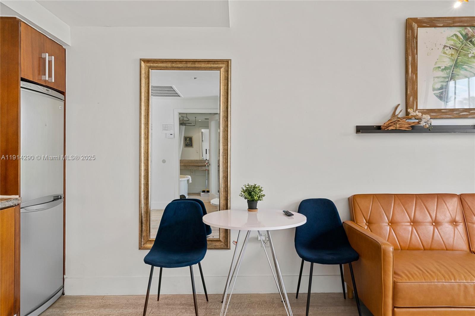 A small dining area features a white table, two blue chairs, and a large mirror — 1060 Ocean Dr # D307, Miami Beach FL 33139, MIAMI BEACH, FL