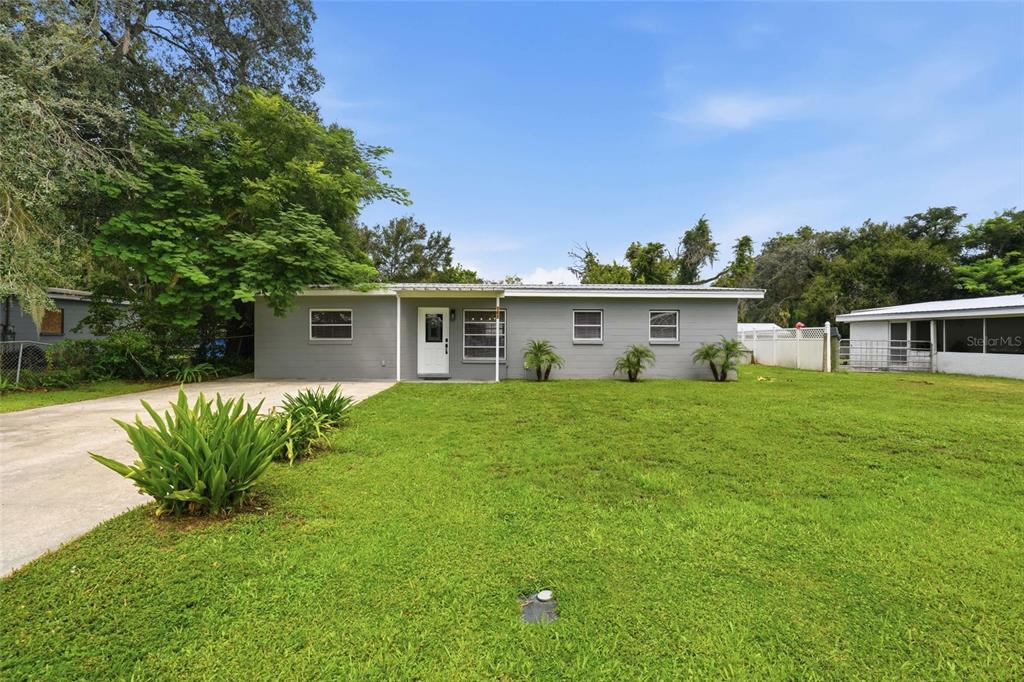 A single-story gray house with a white door and a large front lawn — 162 BRIDLE PATH, ARCADIA, FL