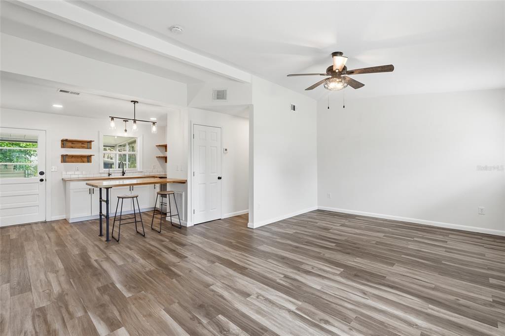An open-concept living area with wood-look flooring, a ceiling fan, and a kitchen breakfast bar — 162 BRIDLE PATH, ARCADIA, FL