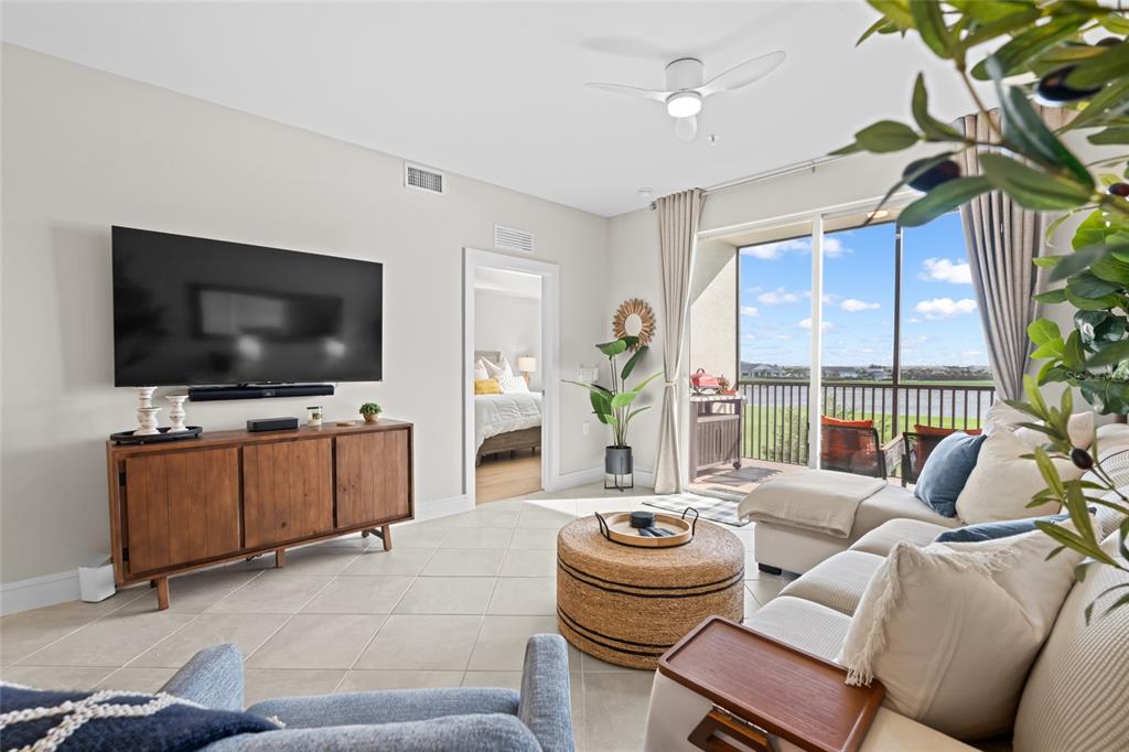 A living room features tile floors, a large television, a sectional sofa, and a balcony — 5651 DOUBLE EAGLE CIRCLE UNIT 4335, AVE MARIA, FL