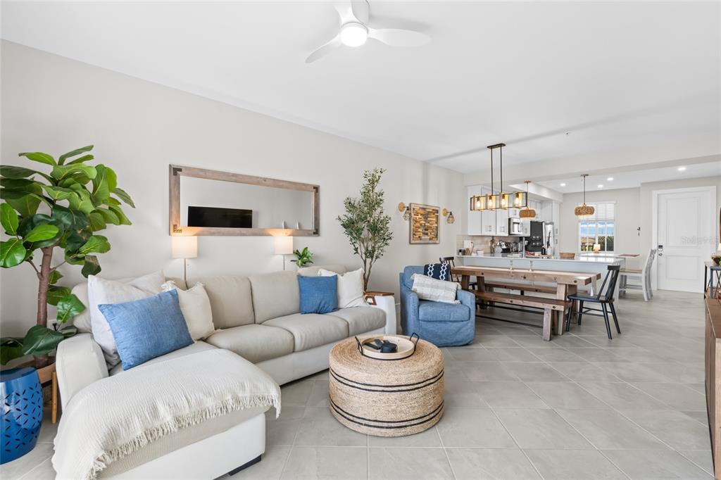 A living room with a sectional sofa, round ottoman, and an adjacent dining area — 5651 DOUBLE EAGLE CIRCLE UNIT 4335, AVE MARIA, FL