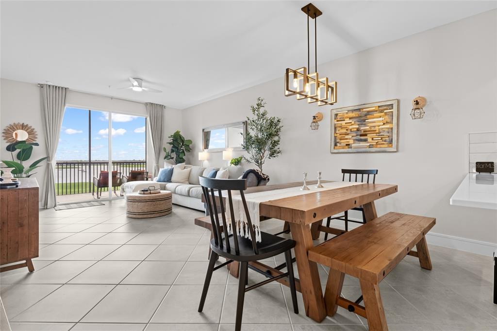 A dining area with a wooden table and bench opens into a living room — 5651 DOUBLE EAGLE CIRCLE UNIT 4335, AVE MARIA, FL