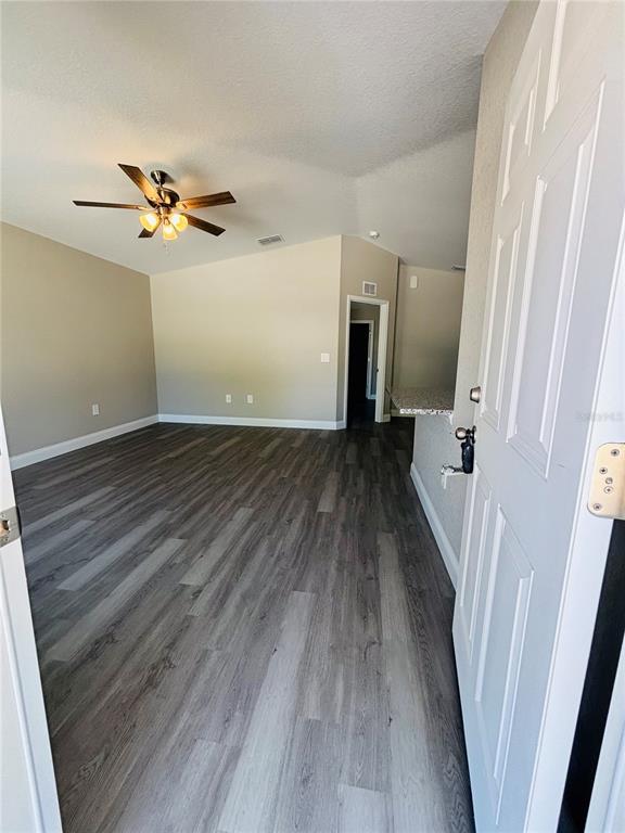 An open living area features gray wood-look flooring, a ceiling fan, and a kitchen counter — 25 PALMETTO AVENUE S, FORT MEADE, FL