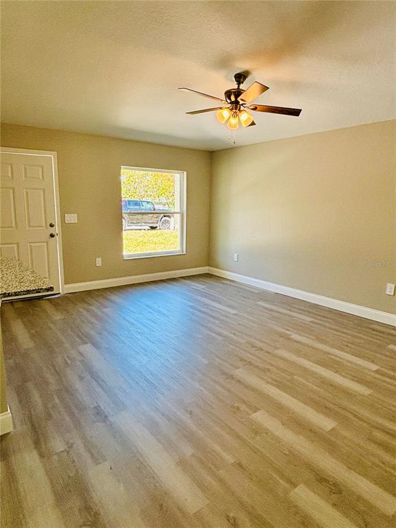 An empty room with light wood-look flooring, a ceiling fan, and a window facing outdoors — 25 PALMETTO AVENUE S, FORT MEADE, FL