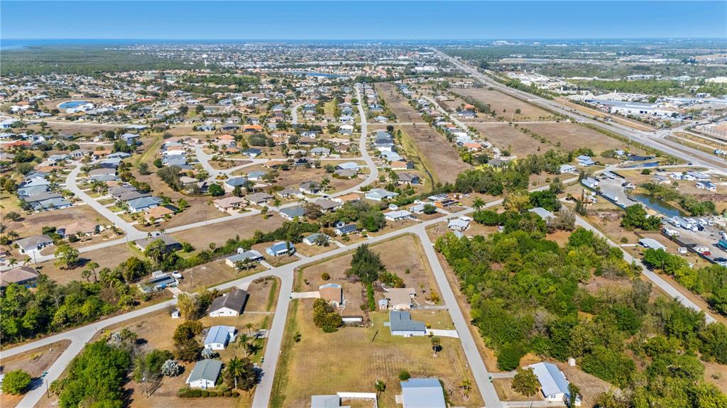 This aerial view shows a suburban neighborhood with single-family homes, paved roads, and surrounding vegetation — 11131 3RD AVENUE, PUNTA GORDA, FL
