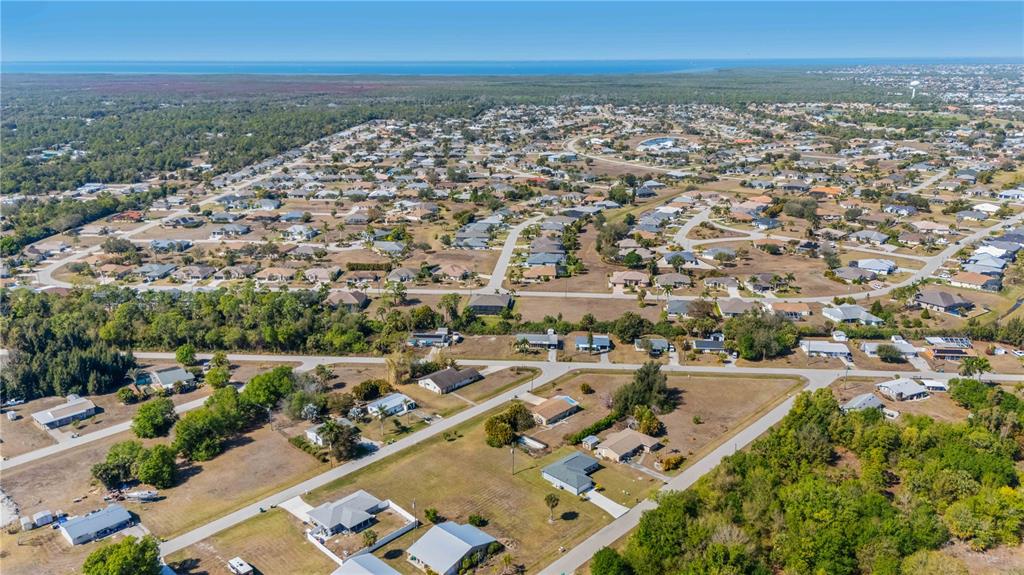 An aerial view shows a residential neighborhood with scattered houses, paved roads, and surrounding wooded areas — 11131 3RD AVENUE, PUNTA GORDA, FL