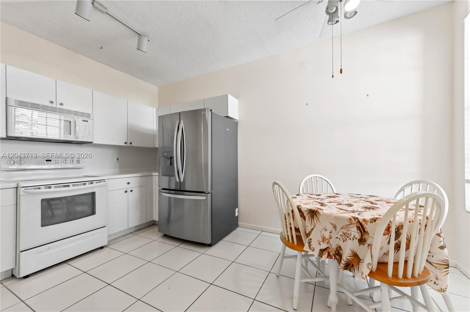 A kitchen features white cabinetry, stainless steel appliances, and a small dining table with chairs — 7874 Laina Ln # 1, Boynton Beach FL 33437, BOYNTON BEACH, FL