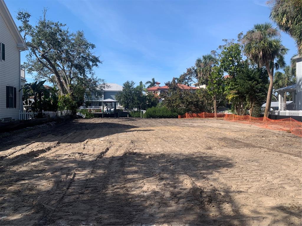 A cleared, sandy residential lot is bordered by houses, trees, and orange construction fencing — 5123 W NEPTUNE WAY, TAMPA, FL
