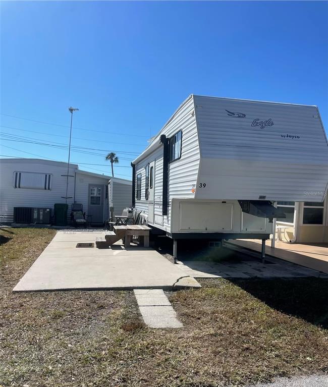 A white Jayco Eagle fifth-wheel trailer sits on a concrete pad next to a mobile home — 39 ILLINOIS STREET, PALMETTO, FL