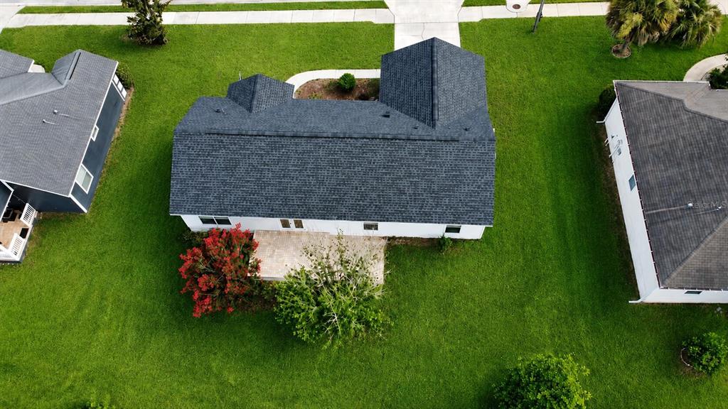 An aerial view shows the dark shingled roof of a house with a backyard patio — 11348 NW 31ST LANE, GAINESVILLE, FL