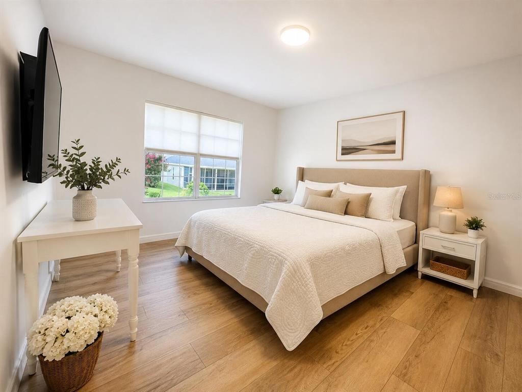 A bedroom features a bed with a beige headboard, white bedding, and light wood flooring — 11348 NW 31ST LANE, GAINESVILLE, FL