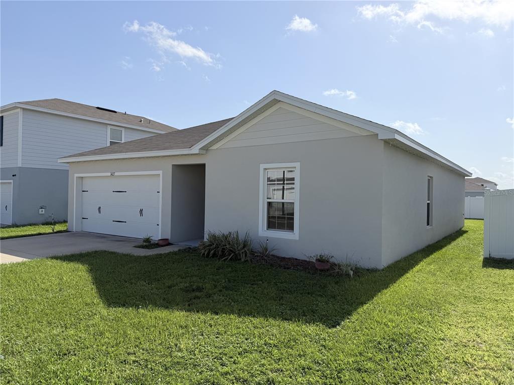 A single-story house with a white garage, gray stucco exterior, and a front lawn — 1427 MADISON CIRCLE, HAINES CITY, FL